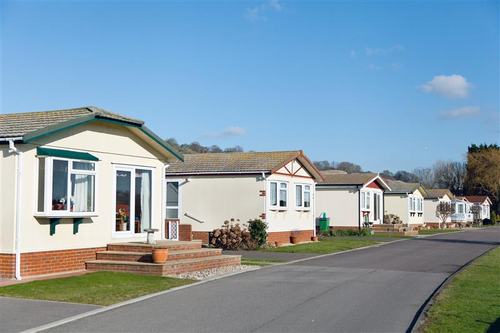 A row of park homes along a road on a park home site – small homes with brick bases and tiled roofs.